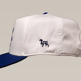 The Shop Hat | Updated Oval by Ballad of the Bird Dog is a white baseball cap with a dark blue brim and a small embroidered dog logo on the side.