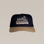 The Shop Hat | Vintage Bird Dog by Ballad of the Bird Dog features "Ballad of The BIRDDOG" and a desert scene embroidered on navy blue and tan, inspired by a classic vintage logo.