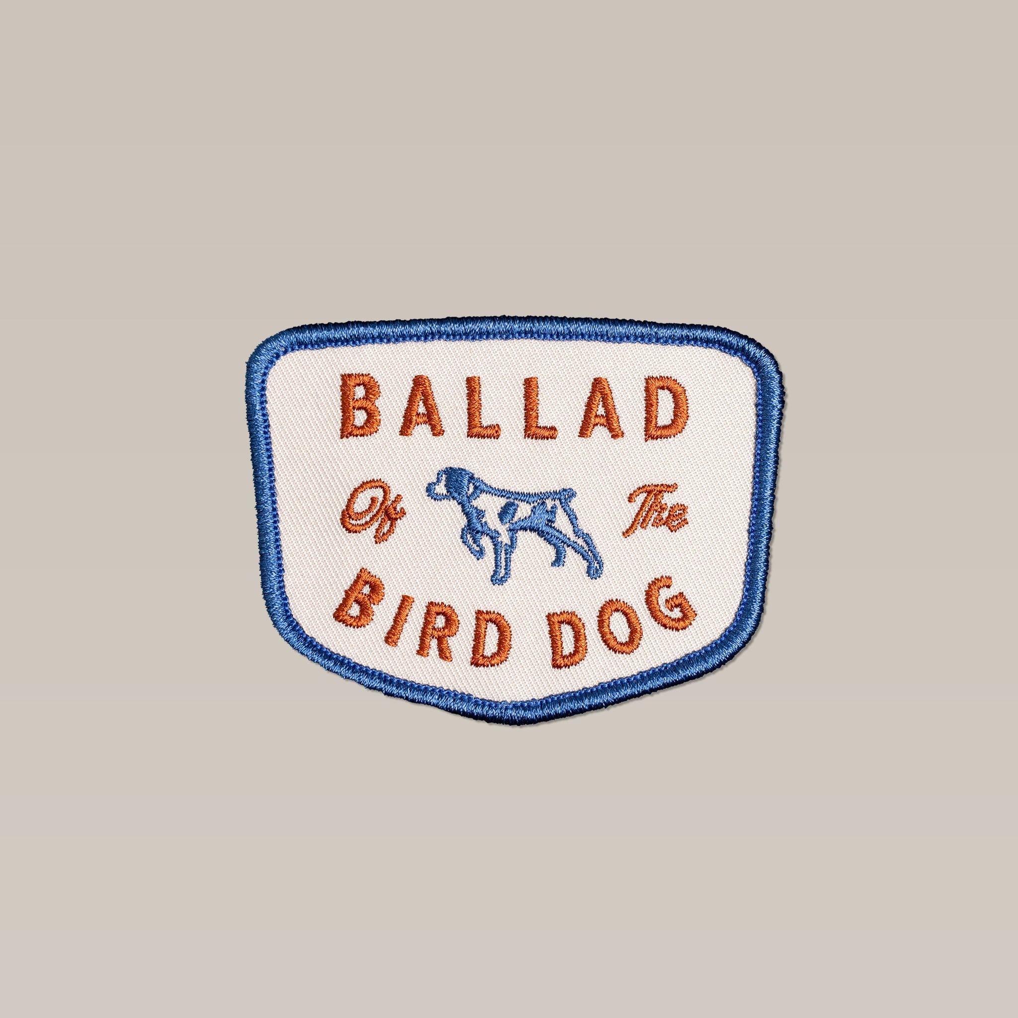 The Shop Patch | Bird Dog Legend features an embroidered dog outline, blue trim, and "BALLAD Of The BIRD DOG" in orange text—an ideal outdoor patch from Ballad of the Bird Dog for any adventure.