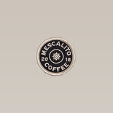 The Classic Circle Logo Patch by Mescalito Coffee is a handmade patch with "MESCALITO COFFEE 2018" in white on black and a simple flower at the center.