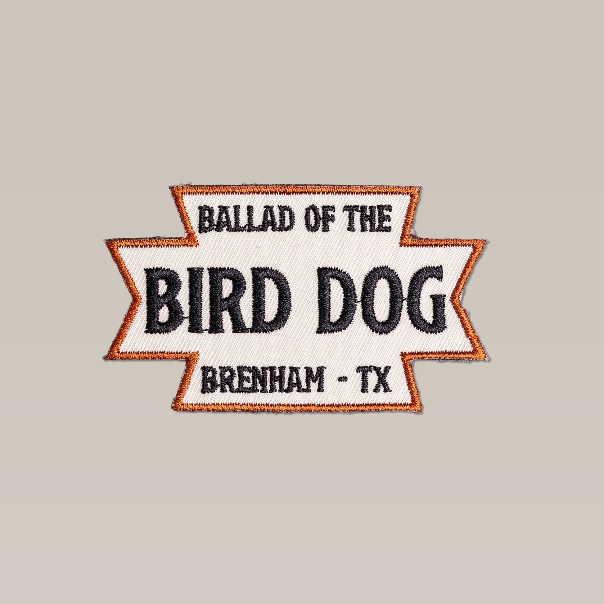 The Shop Patch | Desert Dog by Ballad of the Bird Dog features “Ballad of the Bird Dog Brenham - TX” in black text with an orange border on a light background.
