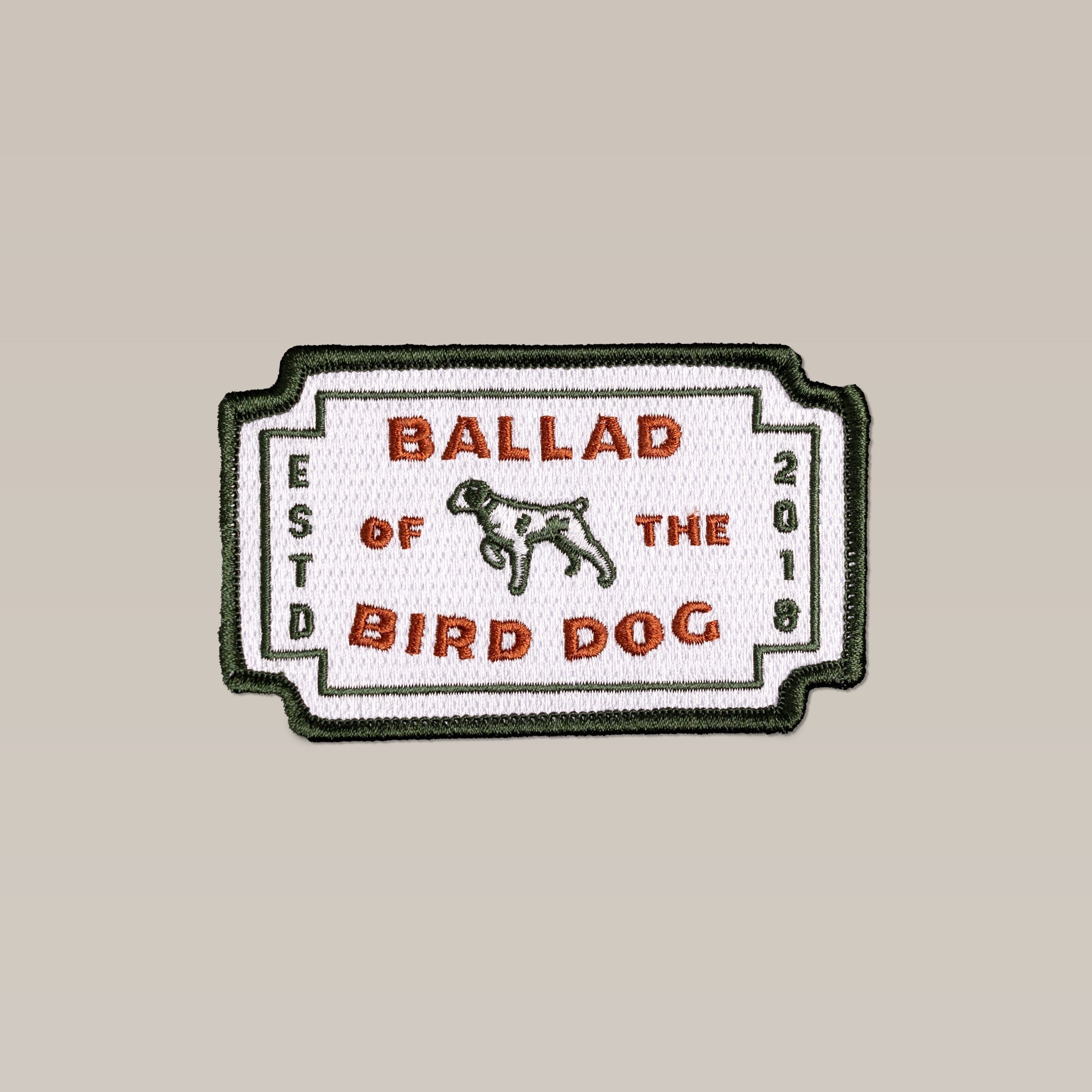 The Ballad of the Bird Dog Shop Patch | Neon Revival features a rectangular embroidered dog logo with "BALLAD OF THE BIRD DOG" and "ESTD 2018" text on a white background, accented by a green border.
