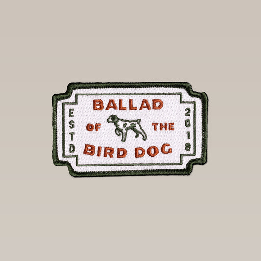The Ballad of the Bird Dog Shop Patch | Neon Revival is a rectangular embroidered patch with a dog graphic and "Ballad of the Bird Dog, ESTD 2018" text on white, plus green and red accents—a timeless classic from Ballad of the Bird Dog.