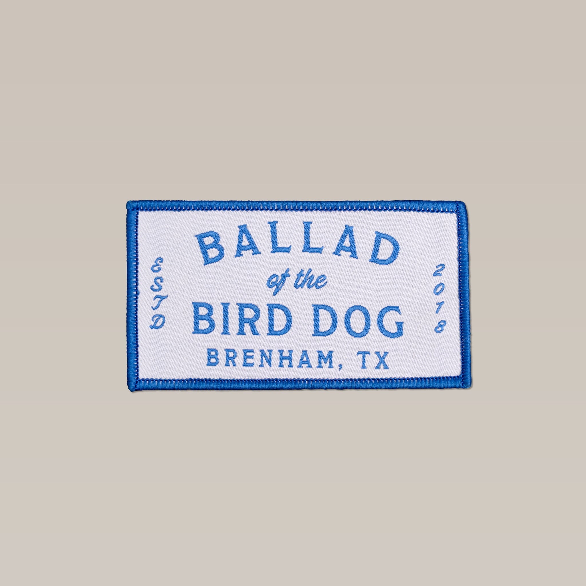The Ballad of the Bird Dog Shop Patch is a rectangular cloth patch with shop logos, blue "Ballad of the Bird Dog, Brenham, TX, ESTD 2018" text on white, and a blue border.