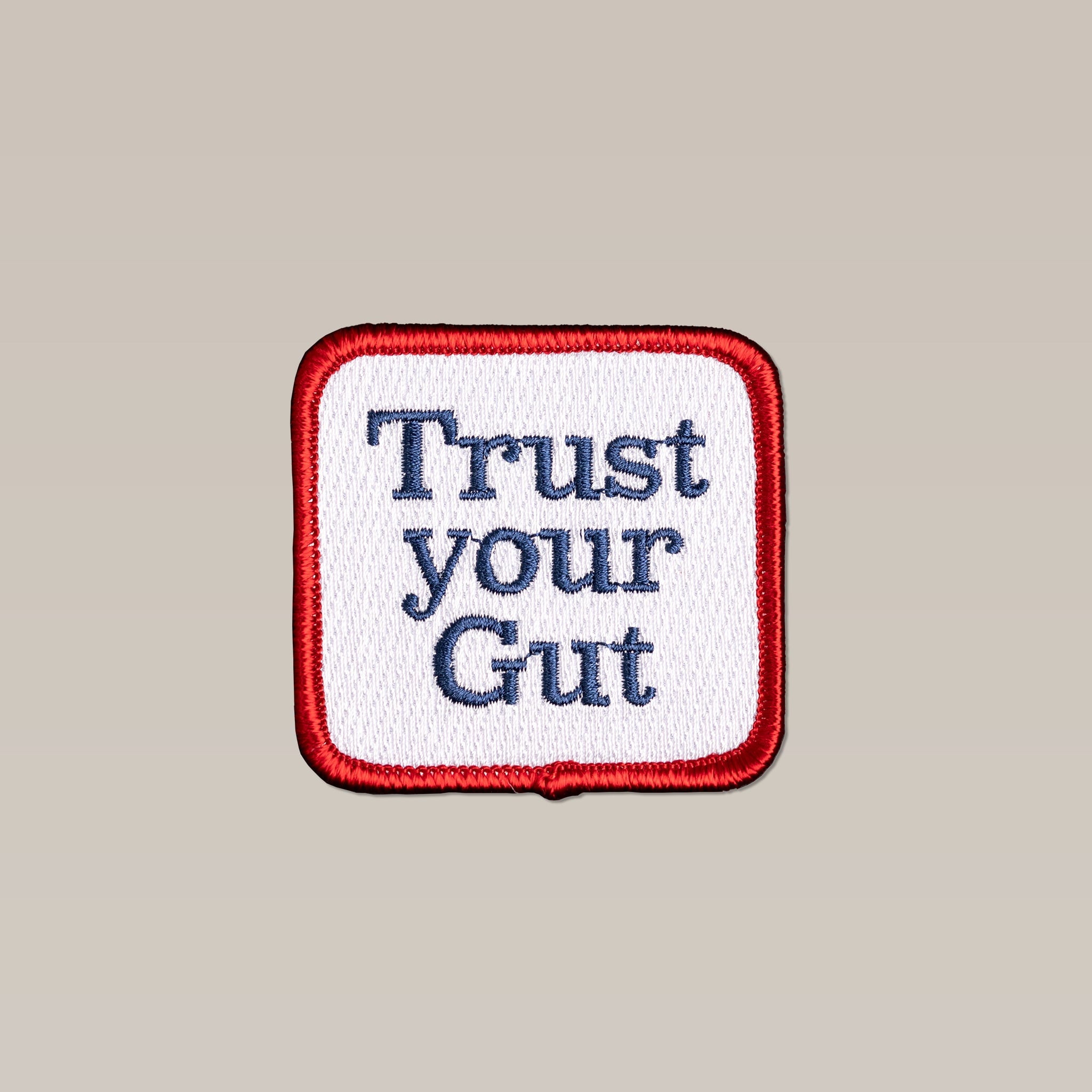 The Ballad of the Bird Dog Shop Patch | Trust Icon is a square embroidered patch with a red border, white center, and "Trust your Gut" in blue—an inspiring emblem for confidence in your instincts.