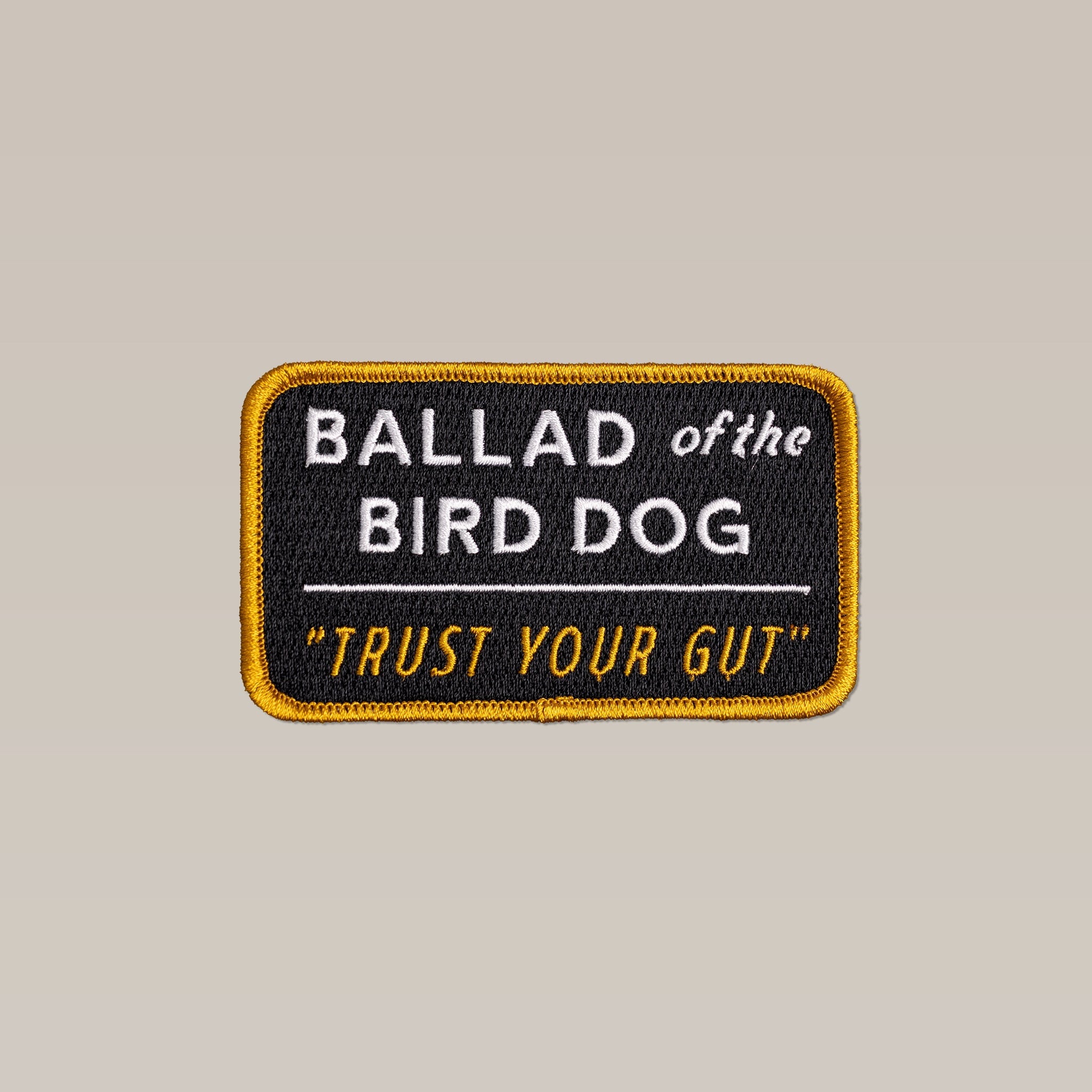 The Shop Patch | Trust Your Gut Vintage Slate by Ballad of the Bird Dog is a rectangular embroidered patch with a yellow border, featuring "BALLAD of the BIRD DOG" and "TRUST YOUR GUT" on a vintage slate black background.