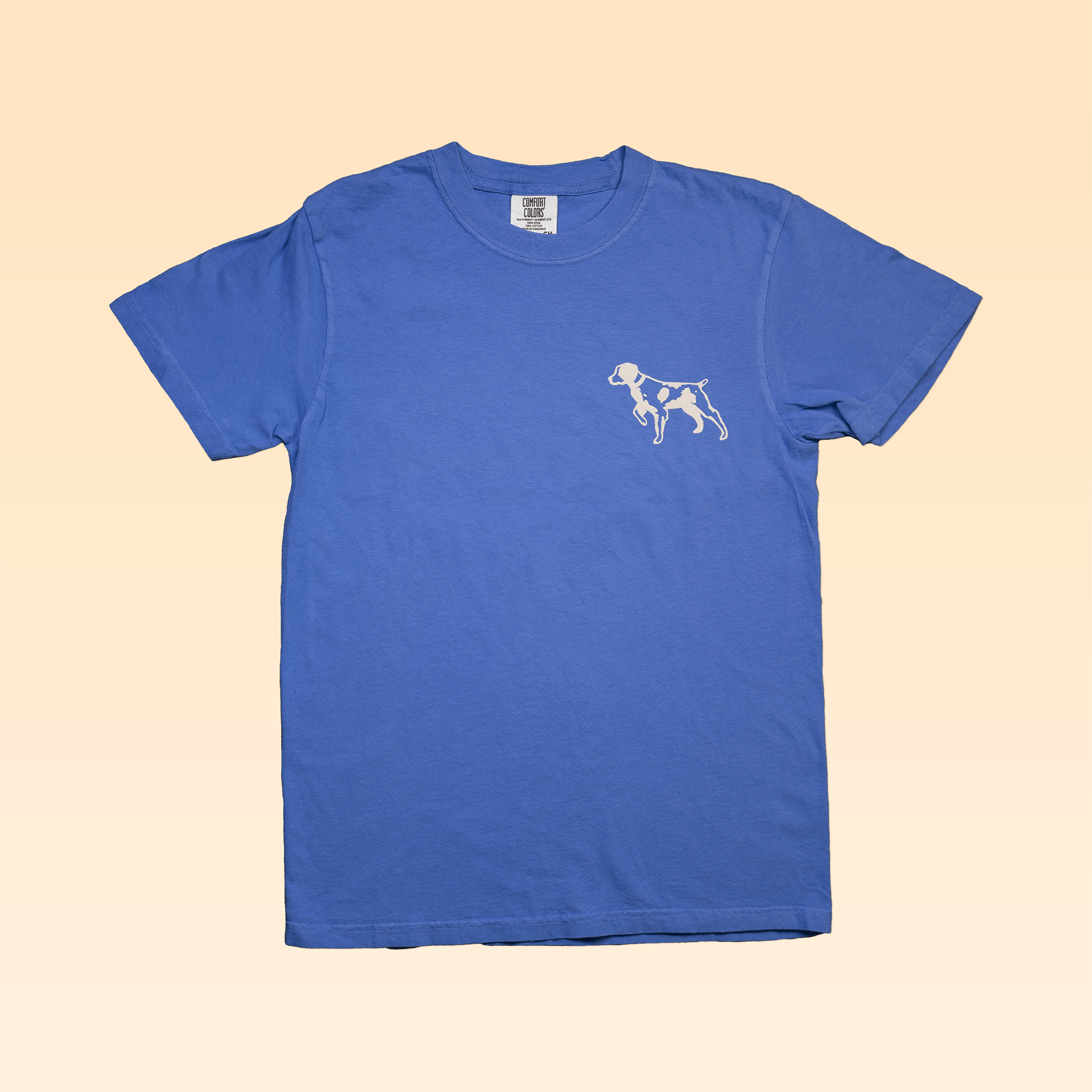 The Ballad of the Bird Dog Shop Shirt features a small white bird dog emblem on plain blue, shown on a light beige background—an ideal way to share your bird dog pride in Downtown Brenham.