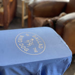 A Shop Shirt featuring the Bird Dog Emblem by Ballad of the Bird Dog is displayed in Downtown Brenham, with leather chairs in the background—showcasing true bird dog pride.