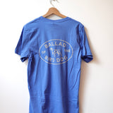 A Shop Shirt | Bird Dog Emblem | Ballad of the Bird Dog by Ballad of the Bird Dog hangs on a wooden hanger, featuring an oval dog logo and "BALLAD OF THE BIRD DOG" text—ideal for showing bird dog pride in Downtown Brenham.