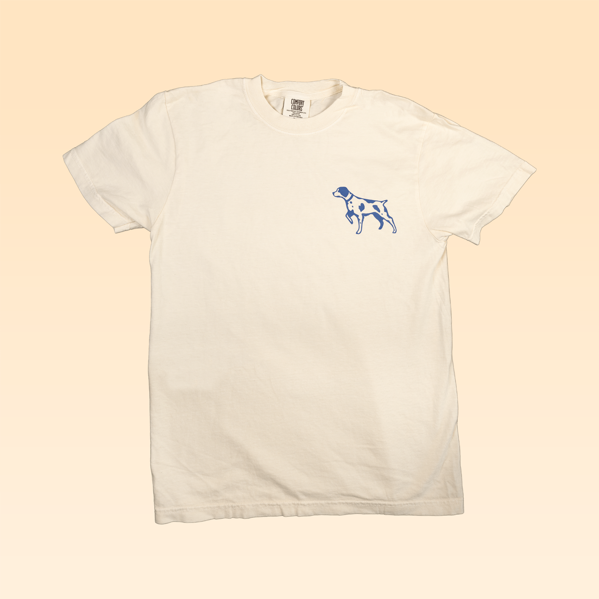 The Shop Shirt | Bird Dog Legend by Ballad of the Bird Dog is a plain white tee with a small blue dog outline on the left chest, inspired by Americana style—perfect for fans. Shown on a light beige background.
