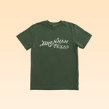 The Shop Shirt by Ballad of the Bird Dog features "Brenham Texas" in white heritage script on green, shown against a beige background—a classic staple for any wardrobe.
