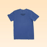 The Shop Shirt | Brenham Water Tank by Ballad of the Bird Dog is a blue short-sleeve tee laid flat, viewed from the back, featuring "BRENHAM TEXAS" in black near the neckline—a great way to show your local pride.