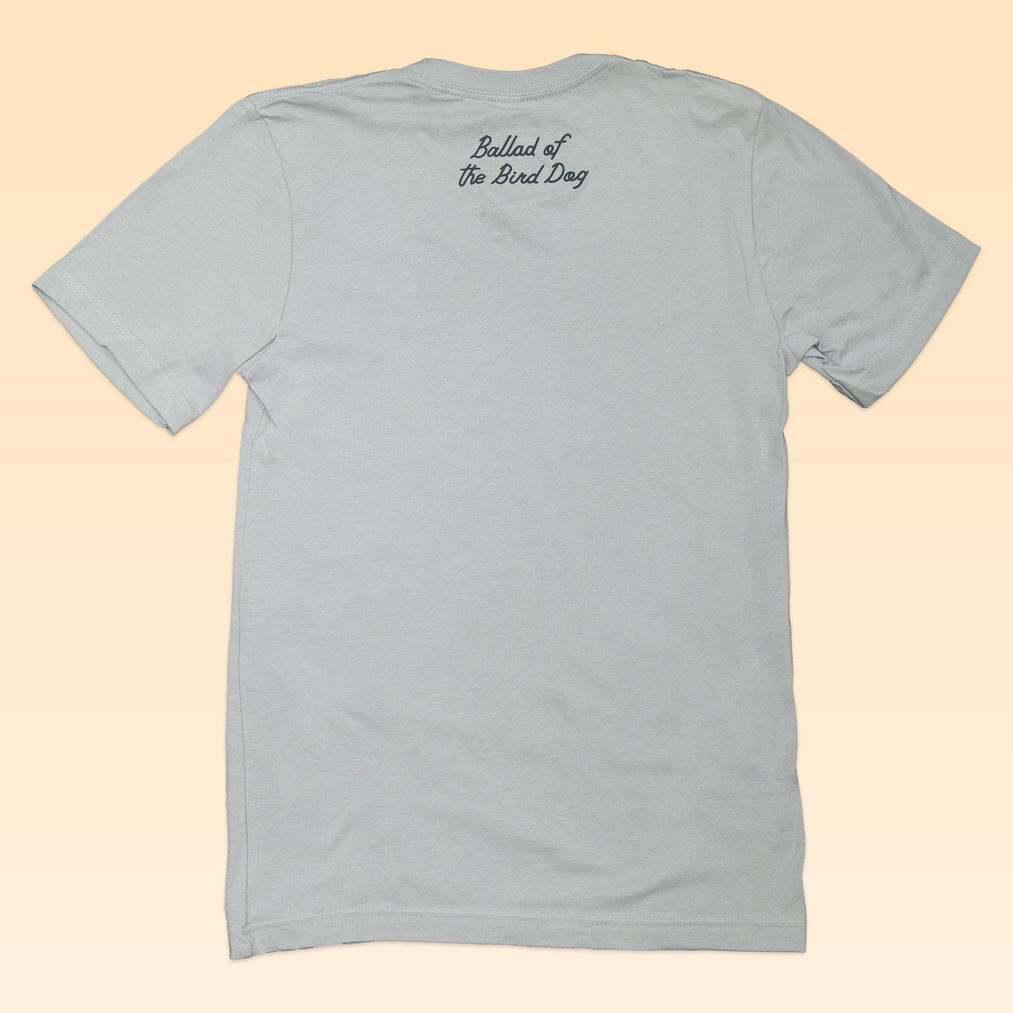 A light gray short-sleeve Shop Shirt by Ballad of the Bird Dog is shown from the back, with “Ballad of the Bird Dog” in small black script near the neckline—perfect for showing off Texas pride and love for Brenham.