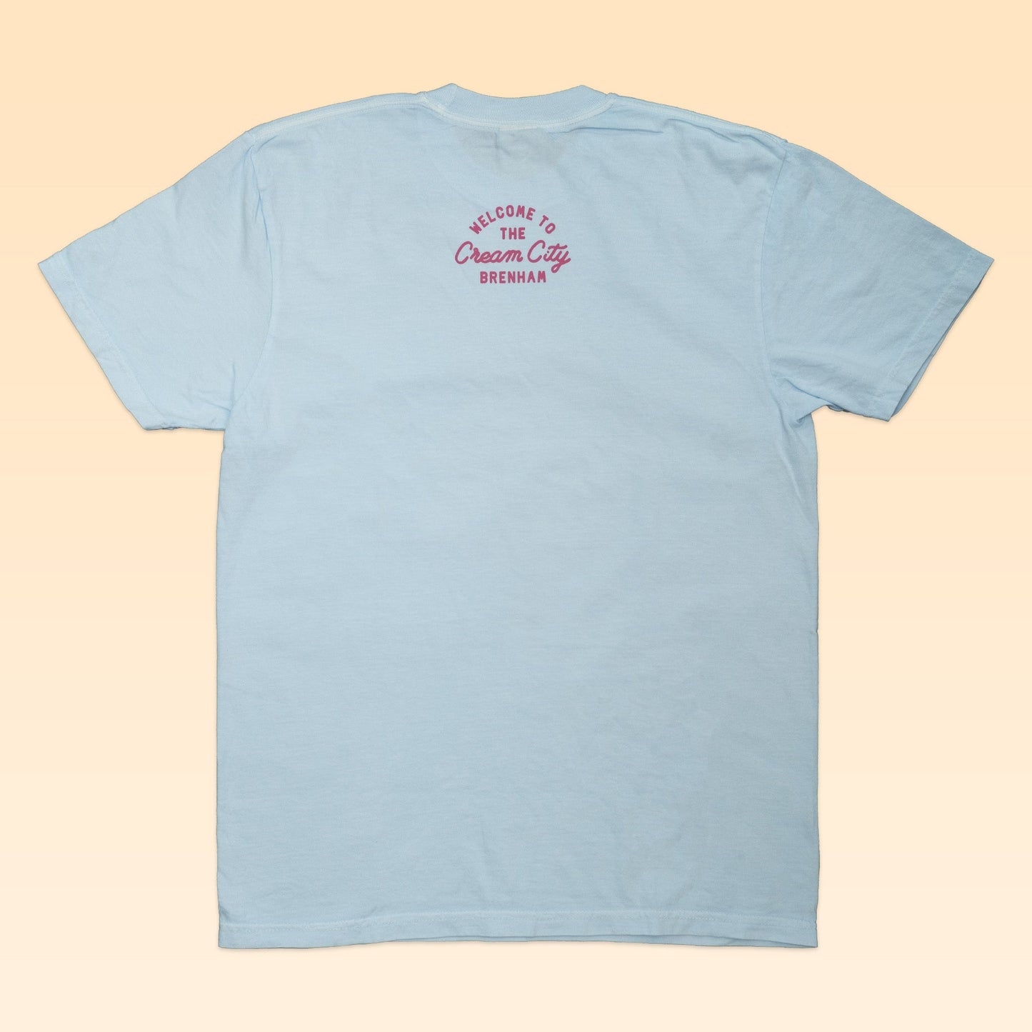 The Shop Shirt | Cream City by Ballad of the Bird Dog is a light blue shirt featuring pink "Welcome to the Cream City Brenham" text near the neckline, celebrating Brenham—home of Blue Bell Creameries.
