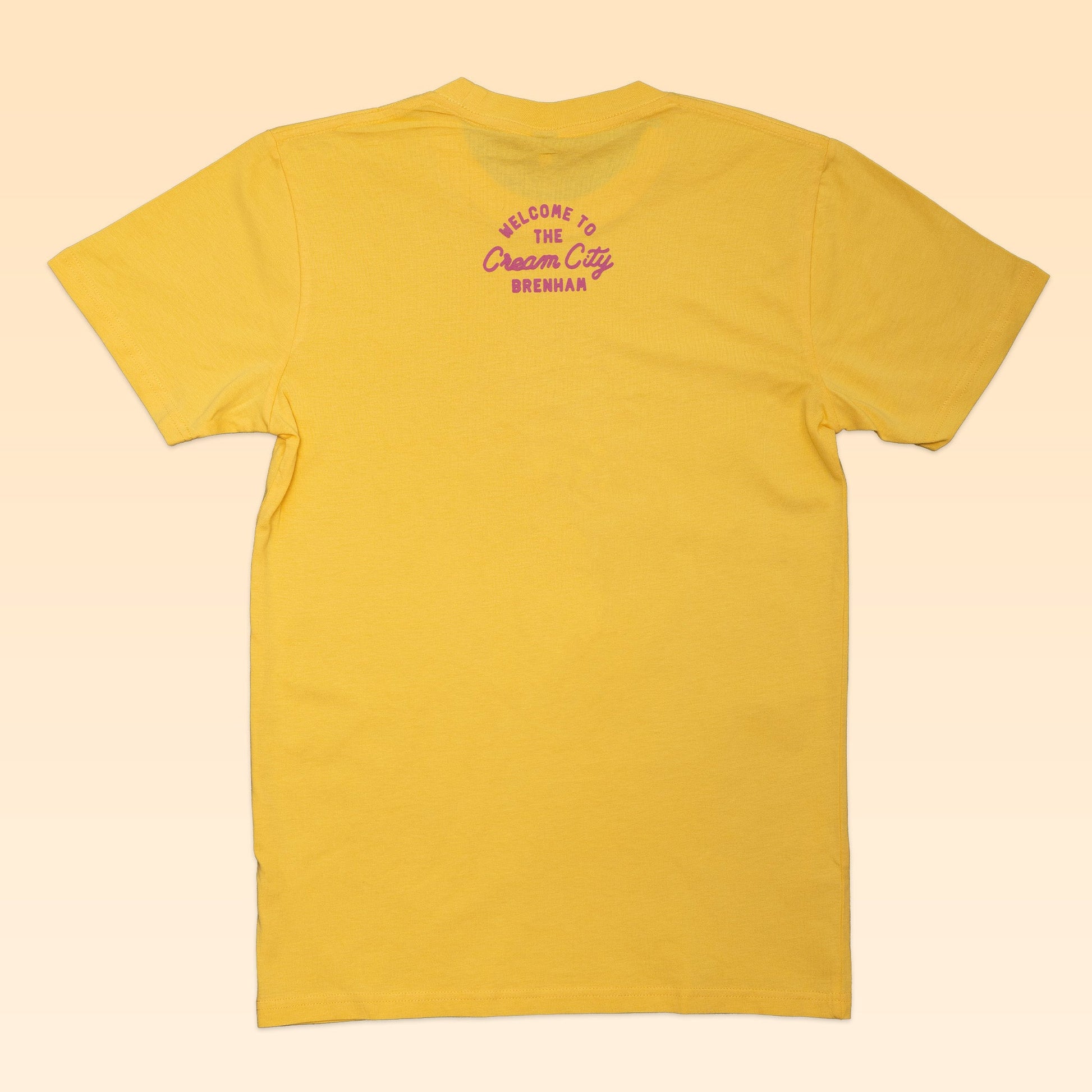 The Ballad of the Bird Dog Shop Shirt | Cream City is shown laid flat, back view, featuring purple "Welcome to the Cream City Brenham" text near the collar to honor Blue Bell Creameries' hometown.
