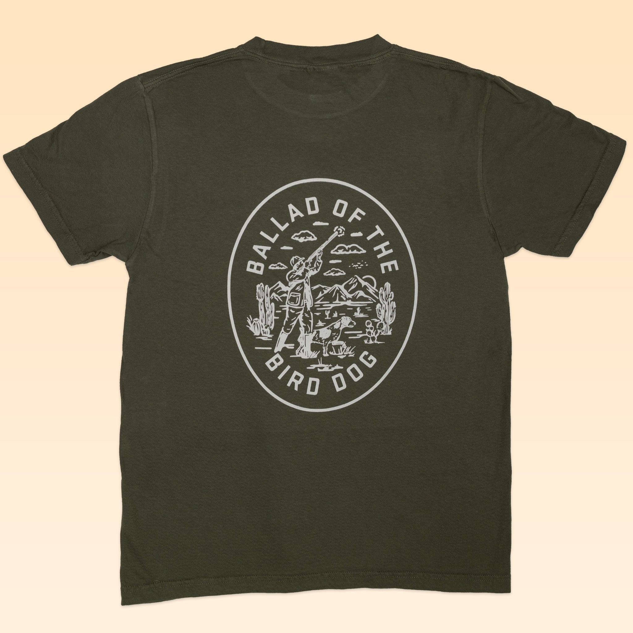 The Shop Shirt | Desert Covey Flush by Ballad of the Bird Dog is an olive green, hand-printed outdoor tee with a white back graphic of a cowboy, dog, desert scene, and "Ballad of the Bird Dog" text.