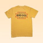The Shop Shirt | Desert Dog by Ballad of the Bird Dog is a yellow tee featuring a bold red and black "Ballad of the Bird Dog" and "Trust Your Gut" graphic on the back, inspired by the adventurous spirit of the American West.