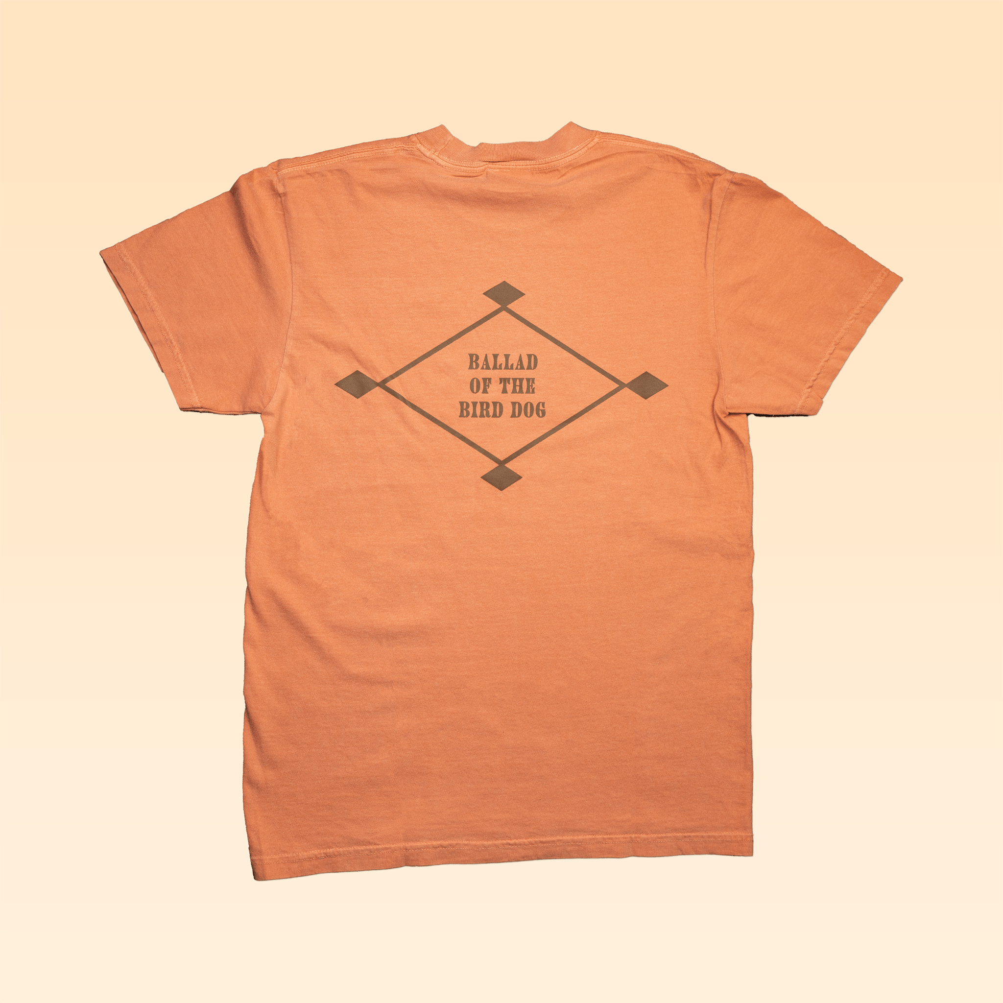 The Shop Shirt | Diamonds by Ballad of the Bird Dog is a peach hand screen-printed shirt featuring a diamond design and "BALLAD OF THE BIRD DOG" on the back.