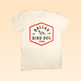 The Ballad of the Bird Dog Shop Shirt | Field Companion features a hexagonal heritage emblem on the back reading "Ballad of the Bird Dog Texas," with a black dog outline inside the logo.