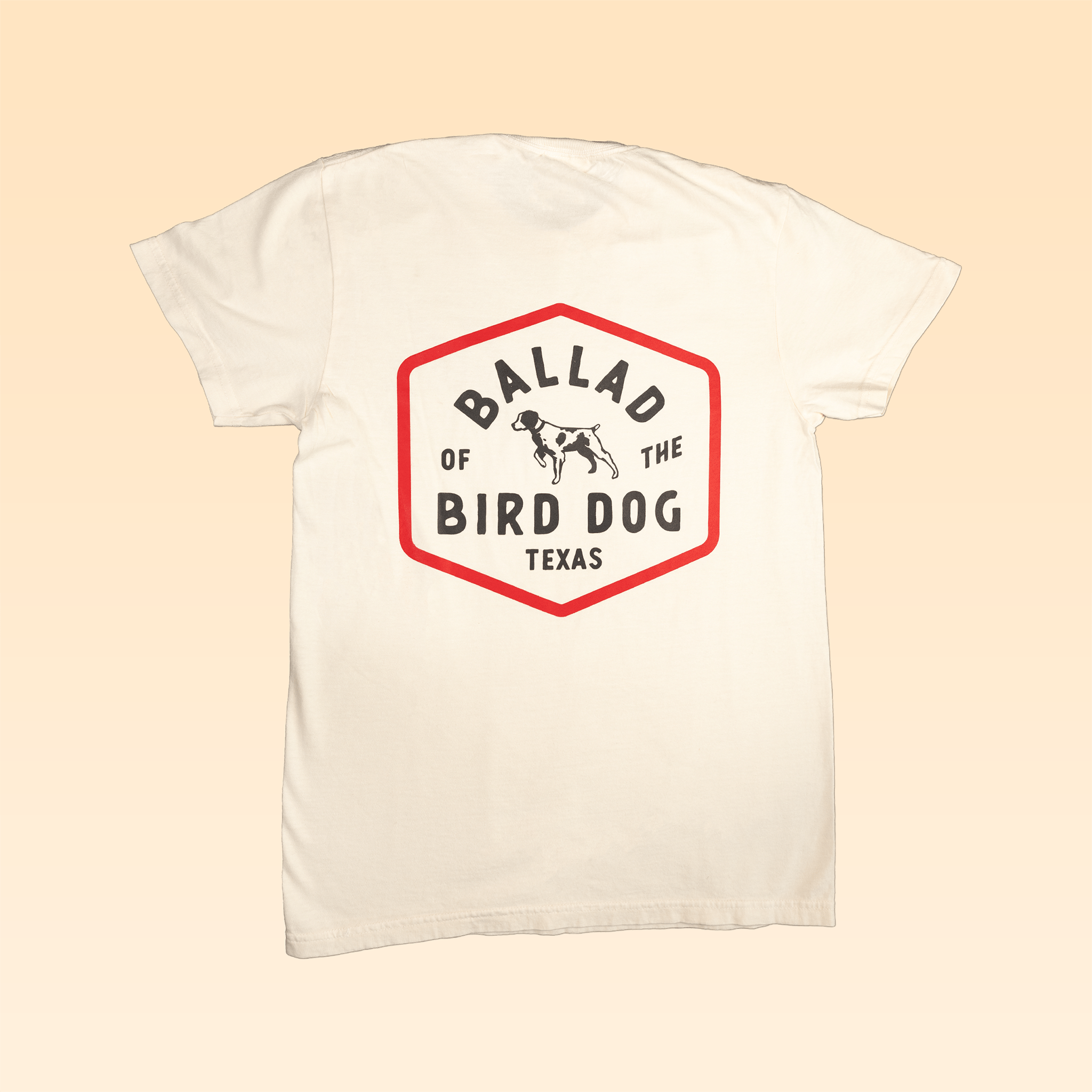 The Ballad of the Bird Dog Shop Shirt | Field Companion features a hexagonal heritage emblem on the back reading "Ballad of the Bird Dog Texas," with a black dog outline inside the logo.
