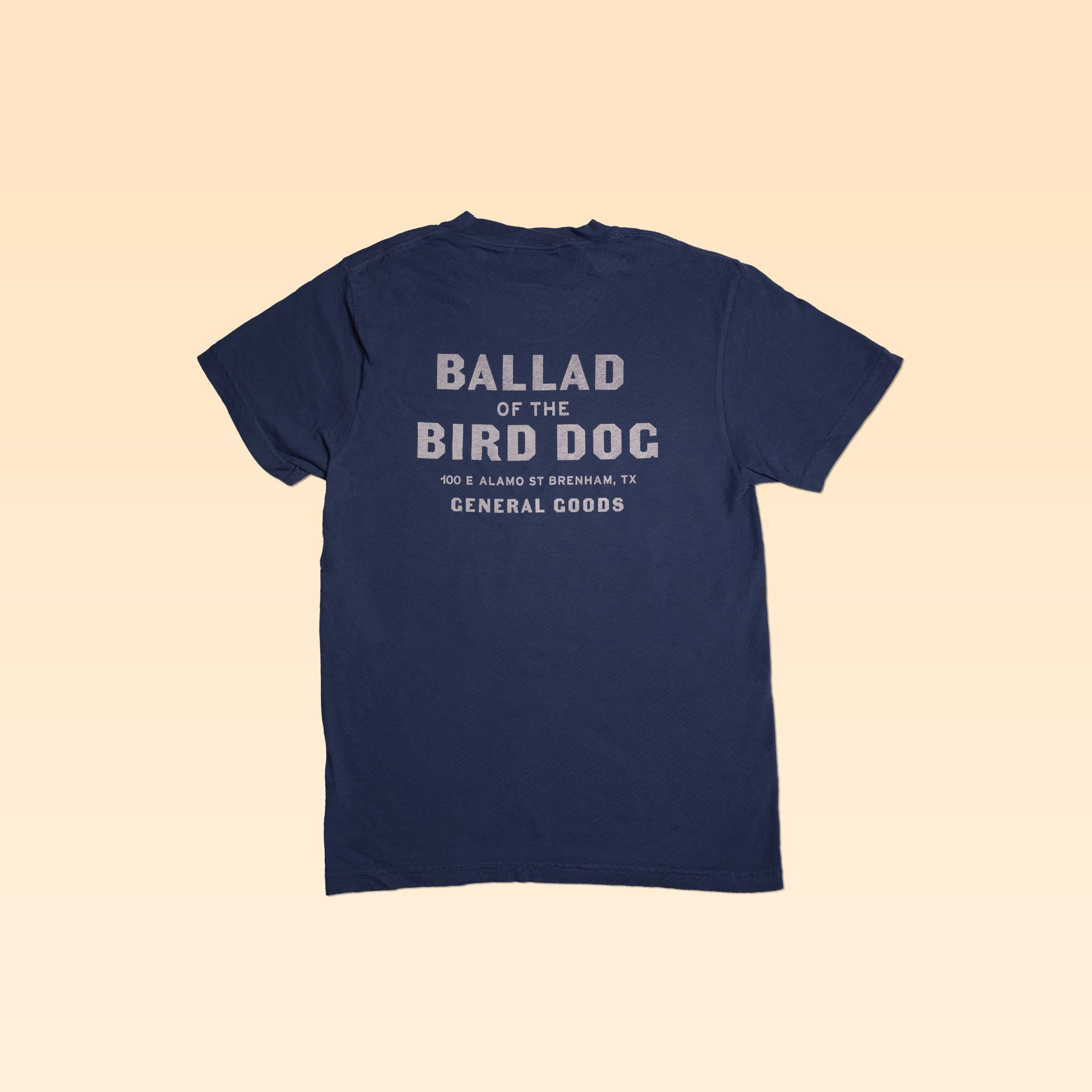 The Shop Shirt from Ballad of the Bird Dog is a navy tee with "BALLAD OF THE BIRD DOG, 100 S ALAMO ST, BRENHAM, TX, GENERAL GOODS" in white—a tribute to the beloved general goods store in Downtown Brenham.