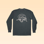 Long-sleeve Shop Shirt by Ballad of the Bird Dog featuring a dark design with a rattlesnake oval graphic and "Ballad of the Bird Dog Texas" text on the back.