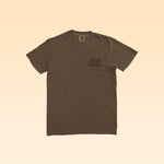 The Ballad of the Bird Dog Shop Shirt | Loyal to The Land is a brown short-sleeve tee with “BALLAD OF THE BIRD DOG” on the left chest, shown on a light gradient background.