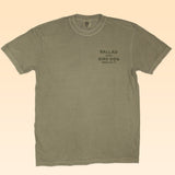 The Shop Shirt | Neon Revival by Ballad of the Bird Dog features a vintage logo and "Ballad of the Bird Dog, Brenham, TX" on sage green Comfort Colors—perfect nostalgic style for classic apparel fans.