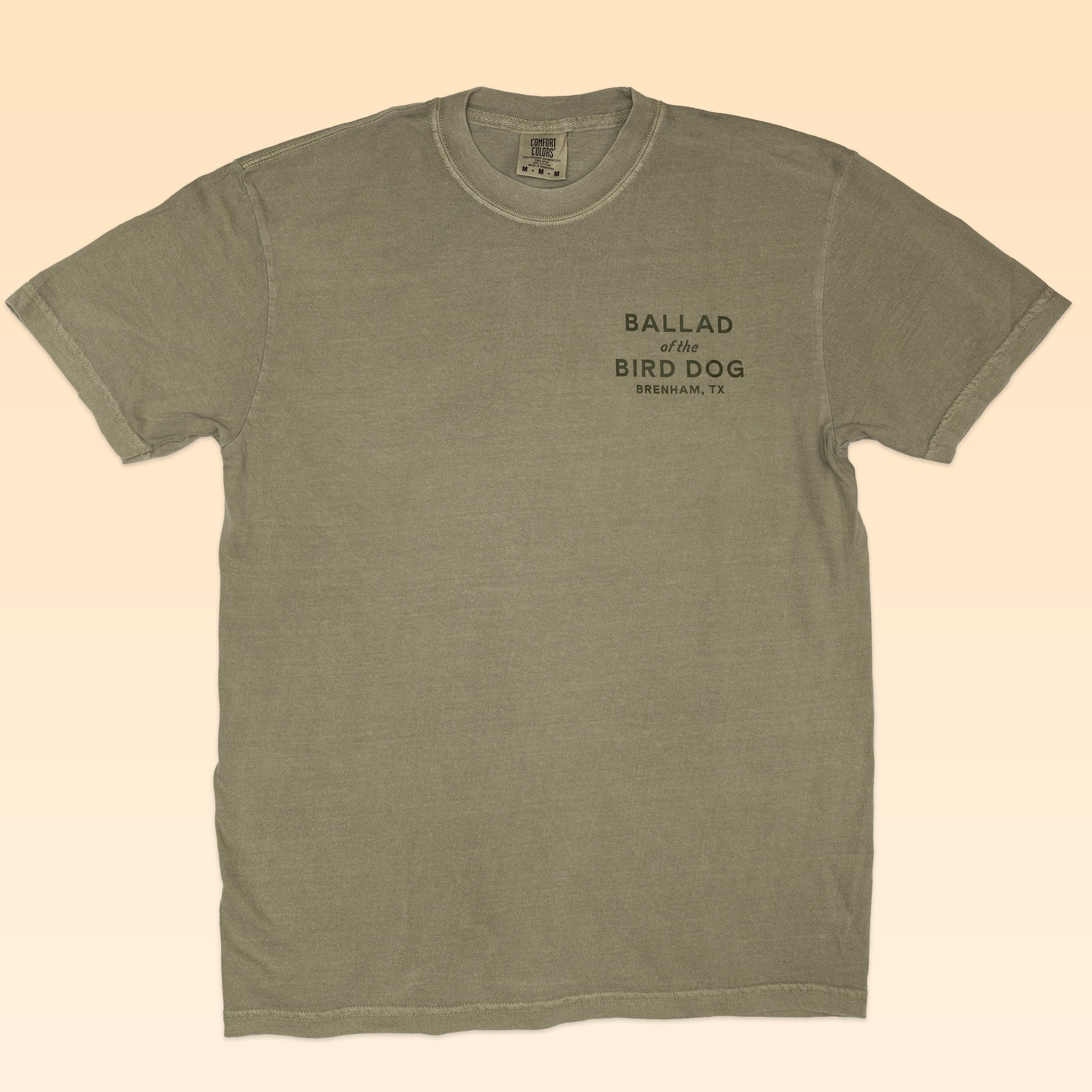 The Shop Shirt | Neon Revival by Ballad of the Bird Dog is an olive green short-sleeve tee with "BALLAD of the BIRD DOG SHERMAN, TX" in black on the left chest—a classic logo shirt from Ballad of the Bird Dog.