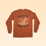 The Shop Shirt | Pheasant Flush by Ballad of the Bird Dog features a rust hue and a back graphic of a dog, pheasants, and plants—blending standout style with comfort.