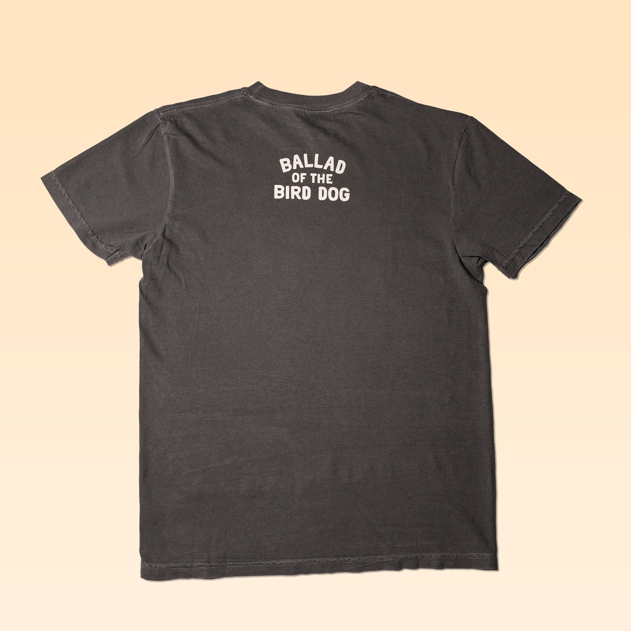 The Ballad of the Bird Dog "Shop Shirt | Pointer" in charcoal gray features "BALLAD OF THE BIRD DOG" printed in white on the upper back, shown laid flat on a beige background.
