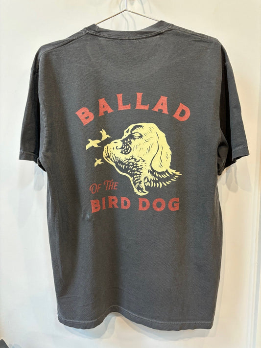 The Shop Shirt | Retriever by Ballad of the Bird Dog is a dark gray tee featuring a yellow dog's head with flying birds and "Ballad of the Bird Dog" printed in red on the back.