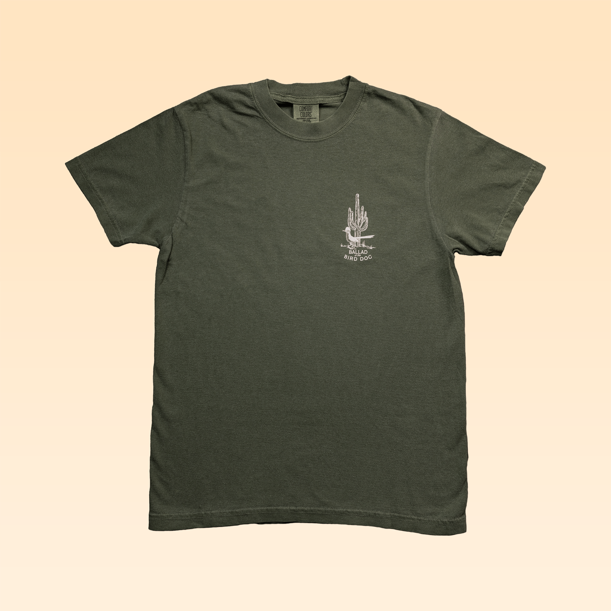 The Ballad of the Bird Dog Shop Shirt in olive green features a small white Roadrunner vs. Rattlesnake graphic and text on the left chest, shown against a plain light beige background.