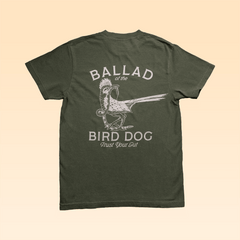 The "Shop Shirt | Roadrunner vs. Rattlesnake" by Ballad of the Bird Dog is an olive green tee with white text and a bird illustration on the back, featuring the phrase "BALLAD of the BIRD DOG Trust Your Gut.