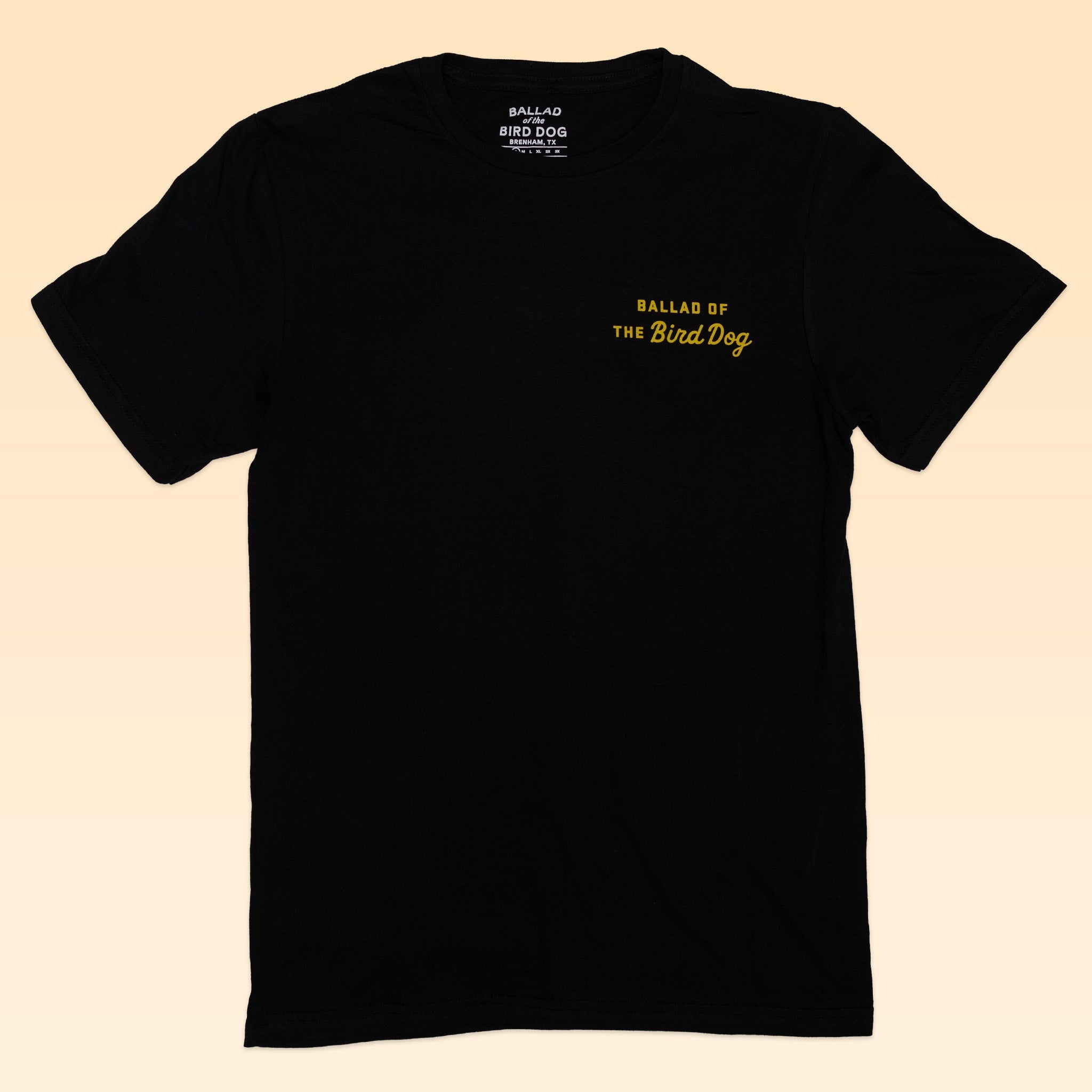 The Ballad of the Bird Dog Shop Shirt | Scorpion is a black tee featuring small yellow "BALLAD OF THE Bird Dog" text on the left chest. Part of the Desert Scenes Collection, laid flat on a light background.