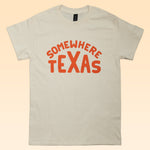 The Shop Shirt | Somewhere Texas by Ballad of the Bird Dog is a beige tee with "SOMEWHERE TEXAS" in bold orange letters—perfect for showing your Texas pride or repping your favorite small-town vibe.