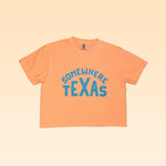 The Shop Shirt | Somewhere Texas Crop by Ballad of the Bird Dog is a peach tee featuring blue "SOMEWHERE TEXAS" text, capturing small-town Texas charm, shown on a light gradient background.