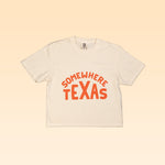 Show your small town Texas pride with the Shop Shirt | Somewhere Texas Crop by Ballad of the Bird Dog—a white cropped tee featuring bold orange "SOMEWHERE TEXAS" print on the front.