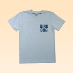 The Shop Shirt by Ballad of the Bird Dog features "BIRD DOG" in bold blue on the left chest, inspired by classic baseball jerseys, in light blue.