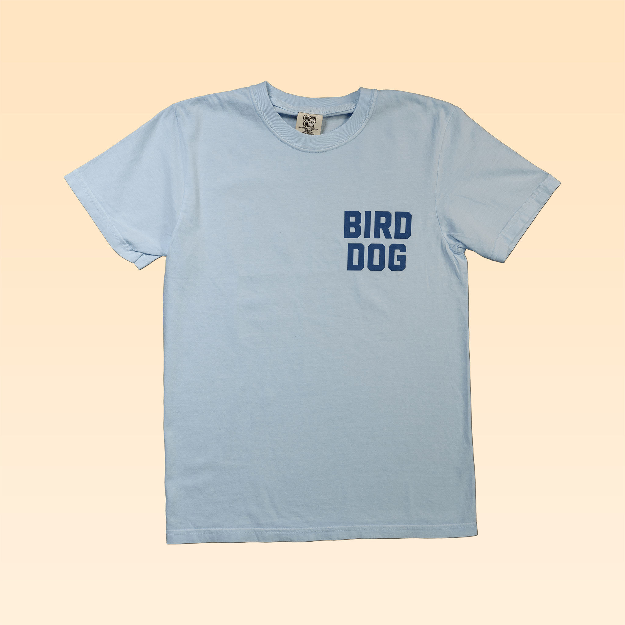 The Shop Shirt by Ballad of the Bird Dog features "BIRD DOG" in bold blue letters on the left chest—a must-have for any bird dog enthusiast.