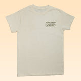 The Shop Shirt | The Wild West by Ballad of the Bird Dog features a cream base with small black chest text: “Rolling in the who and who, passing through the wild west.” Part of our Desert Series for subtle western flair.