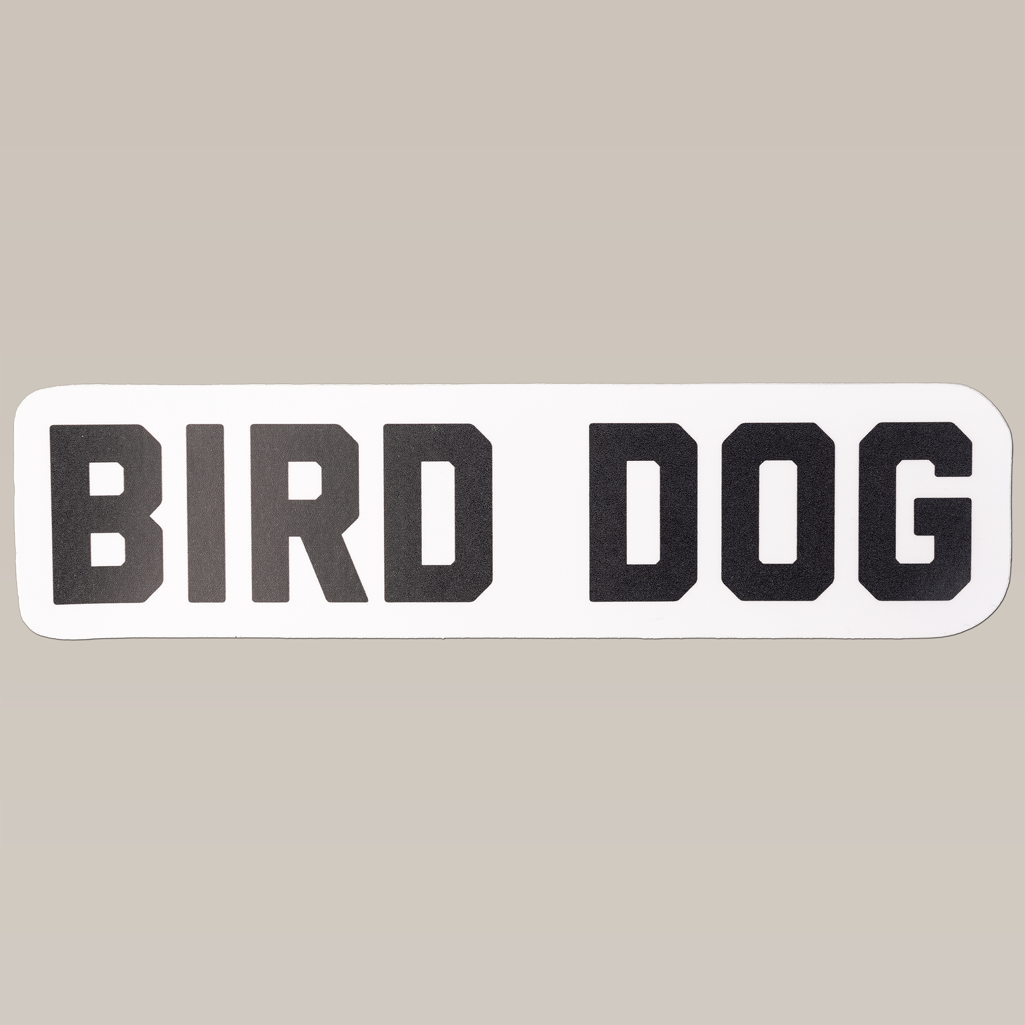 The Shop Sticker | Bird Dog Honor by Ballad of the Bird Dog features bold black "BIRD DOG" text on a white rectangle—ideal for fans of outdoor adventure and bird dog stickers.