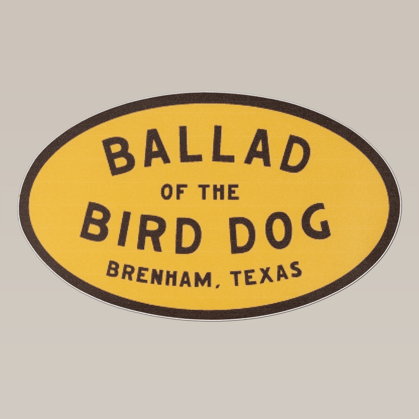 The Shop Sticker | Classic Oval by Ballad of the Bird Dog is a 5-inch yellow oval sticker featuring "Ballad of the Bird Dog, Brenham, Texas" in black text—ideal as a cooler decal.