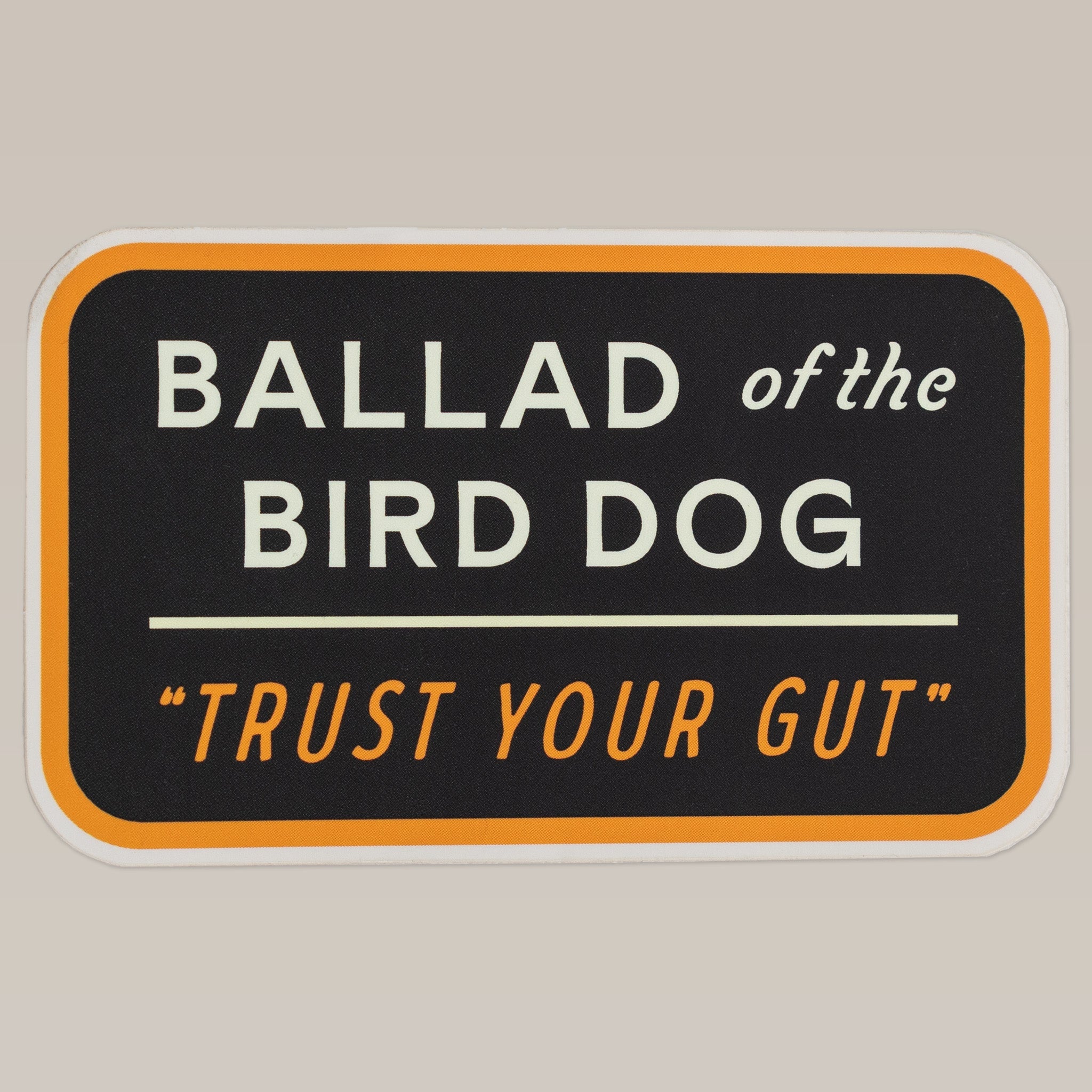 The Shop Sticker | Trust Your Gut Vintage Slate by Ballad of the Bird Dog features "Ballad of the Bird Dog" and "Trust Your Gut" in orange, white, and black text with an orange border in a rectangular vintage patch style.
