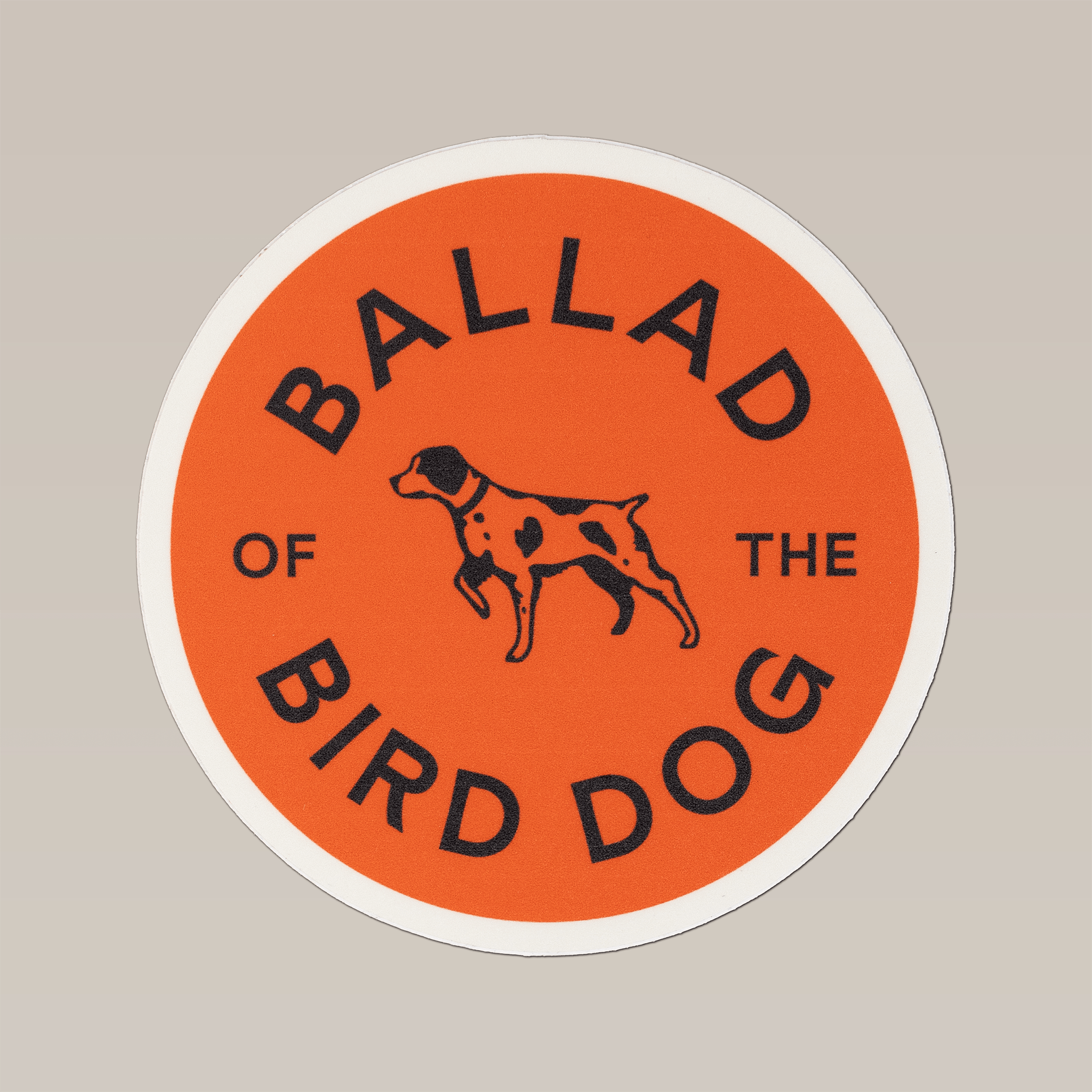 The Ballad of the Bird Dog Shop Sticker features a round, durable orange design with a pointing dog silhouette and black "Ballad of the Bird Dog" text—ideal for coolers or outdoor adventures.