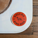 A round, durable Upland Orange Bird Dog Shop Sticker by Ballad of the Bird Dog features a central dog illustration against a white background—ideal for coolers and outdoor adventures.