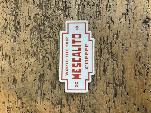 The Shop Stickers | Mescalito Coffee by Mescalito Coffee feature red "WORTH THE TRIP 20 MESCALITO 18 COFFEE" text on a wood-textured background, ideal for coffee shop decor or inspiring new cafe designs.