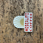 Shop Stickers | Mescalito Coffee by Mescalito Coffee—a sticker featuring bold red "MESCALITO COFFEE" text with a gold sunburst on textured brown wood. Ideal for small-town coffee shop fans or freshening up your coffee shop apparel and accessories.