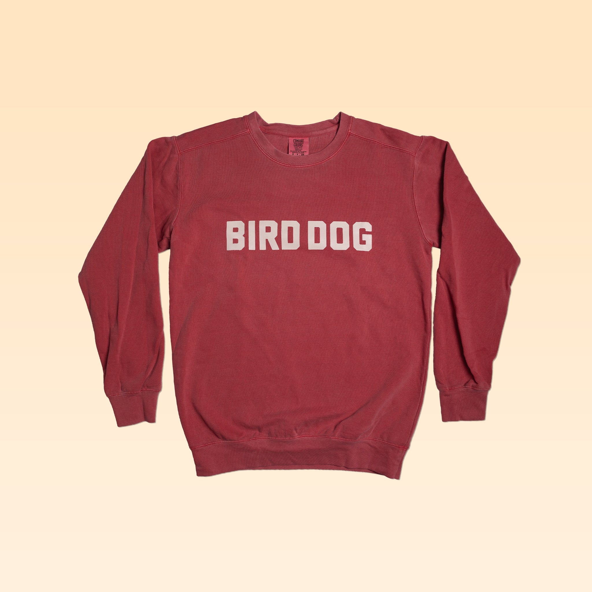 The Ballad of the Bird Dog Shop Sweater | Bird Dog Honor features "BIRD DOG" in bold white letters on the front, shown against a beige gradient background.