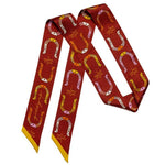 The “Giddy Up” Silk Twilly Scarf by Jenni Earle features red silk, yellow edges, and a repeating multicolored horseshoe pattern with cursive script—a luxe accessory perfect for any collection.